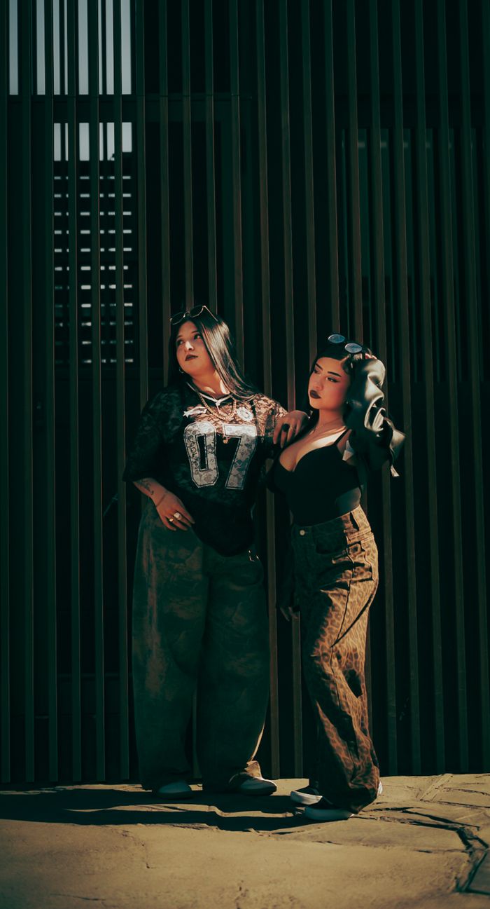 Crafting Captivating Headlines: Your awesome post title goes here Stylish women pose in front of a slatted wall, showcasing urban fashion.