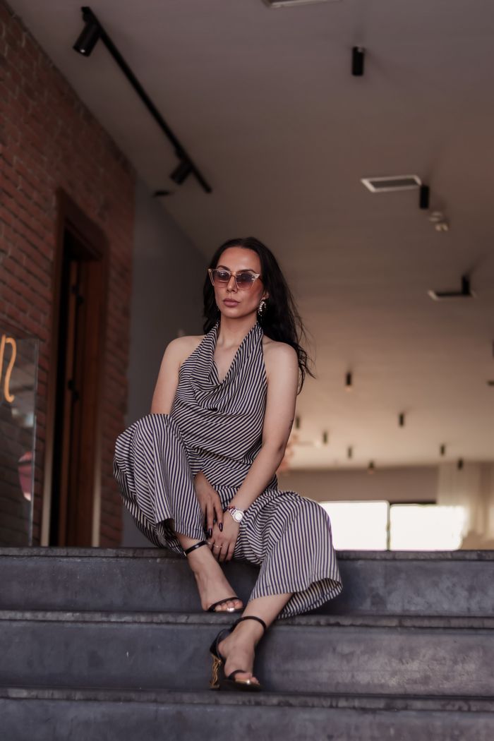 The Art of Drawing Readers In: Your attractive post title goes here Fashionable woman in striped outfit and sunglasses posing confidently indoors.