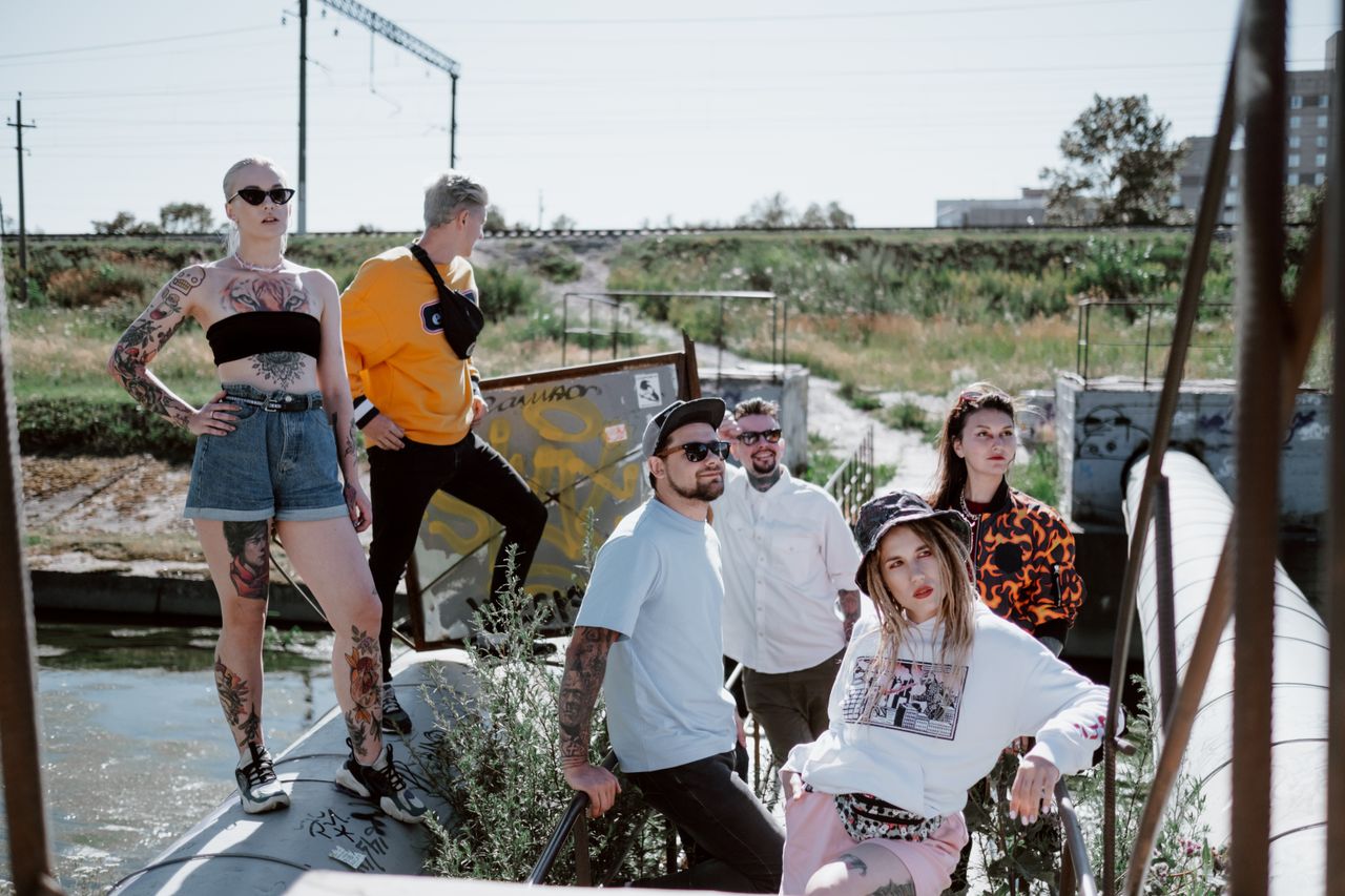 Home Fashionable group posing in streetwear by an industrial outdoor area.