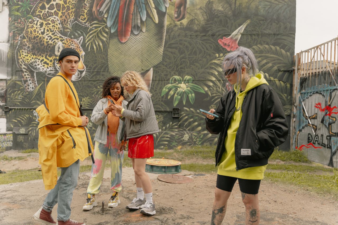 Services A group of diverse friends in stylish streetwear hang out by graffiti art outdoors.