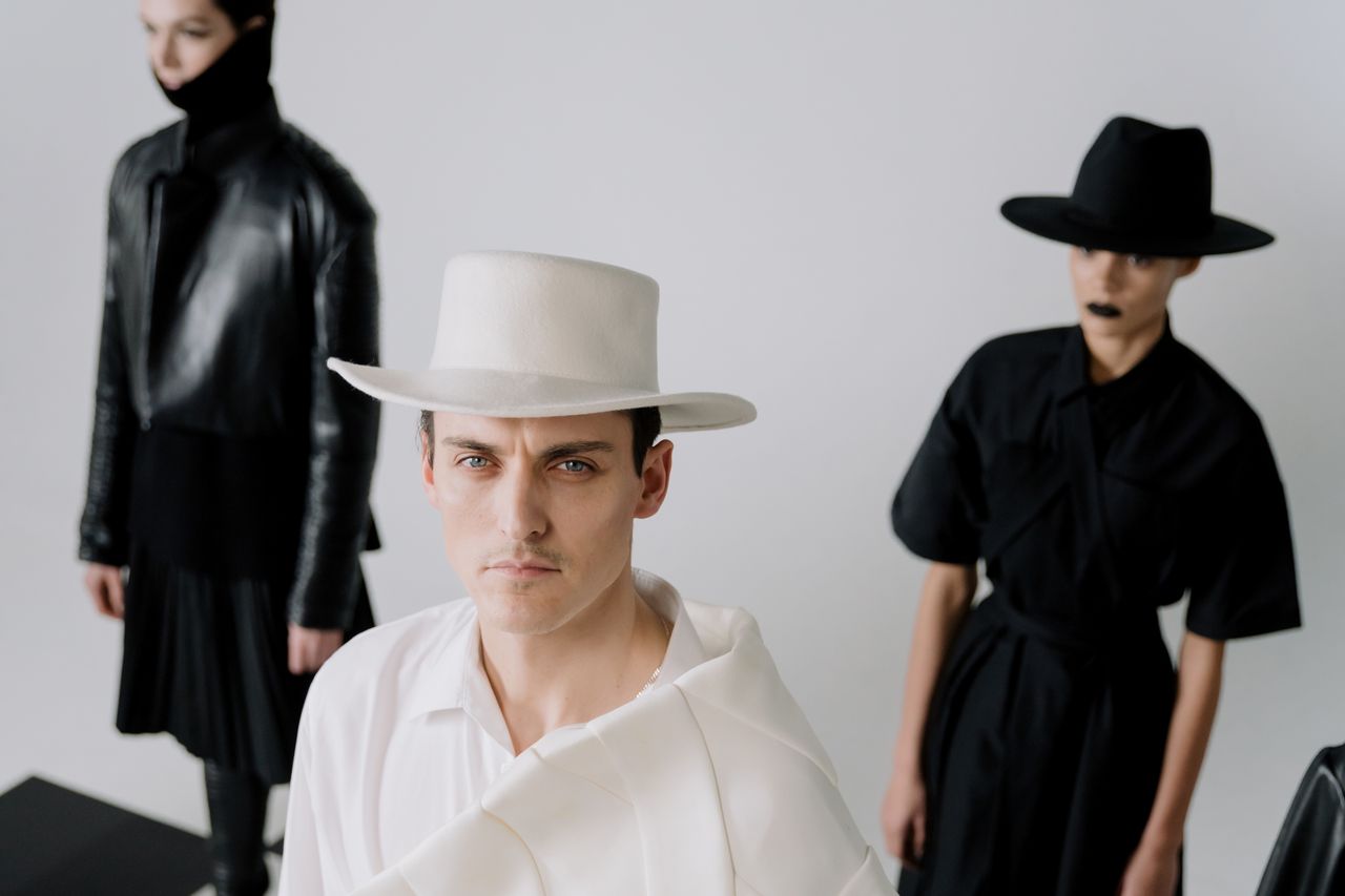 Services Stylish individuals in monochrome fashion with distinctive hats posing indoors.