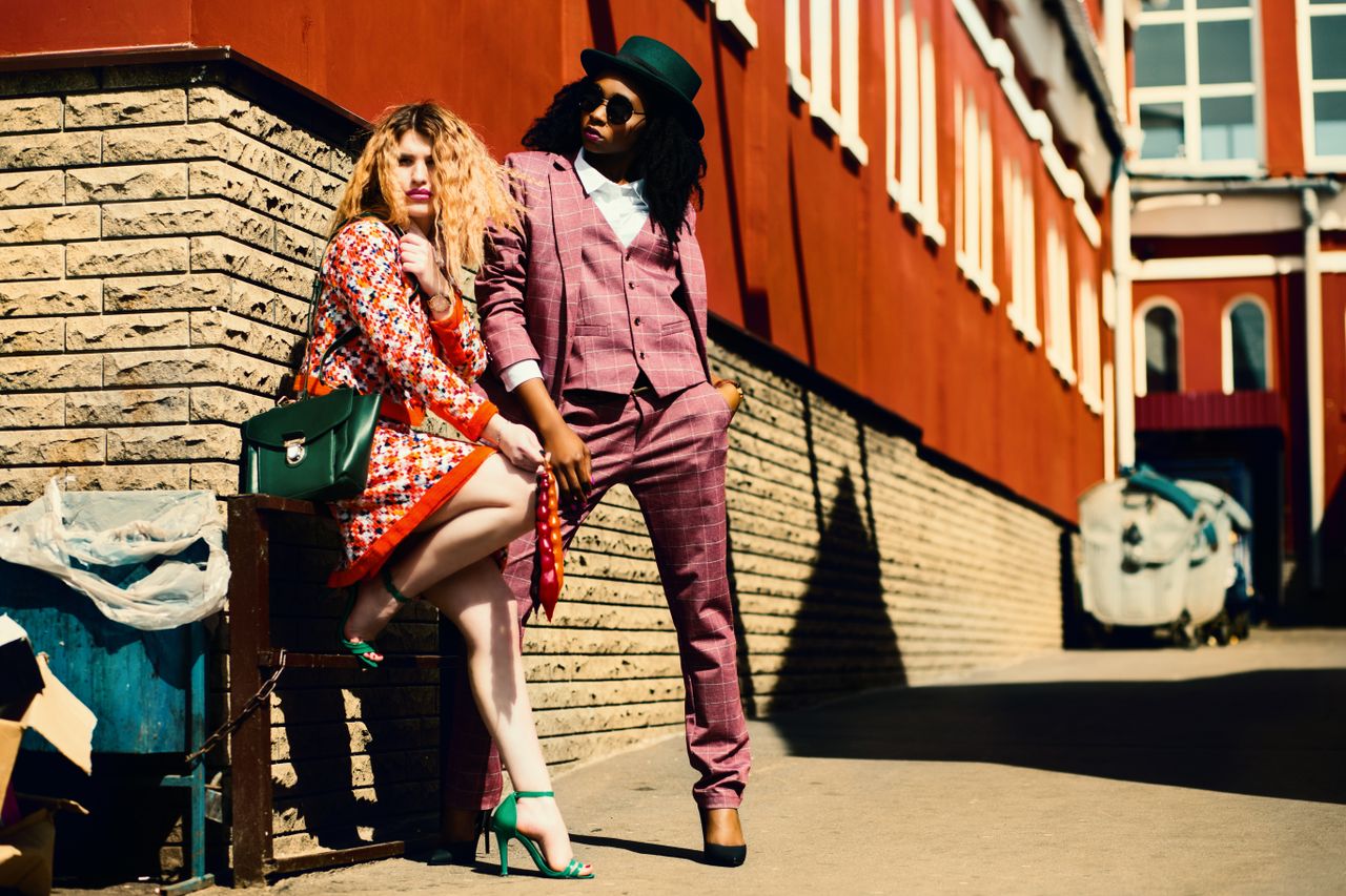 Home Fashionable duo posing outdoors in vibrant outfits, embracing urban style and confidence.